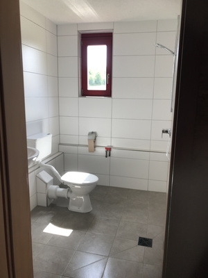 KI generiert: Ein schlichtes Badezimmer mit Toilette und kleinem Fenster.