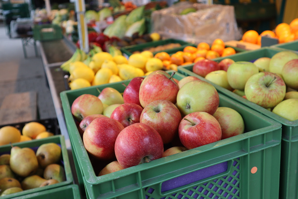 KI generiert: Frisches Obst in grünen Kisten, Äpfel im Vordergrund, auf einem Marktstand.