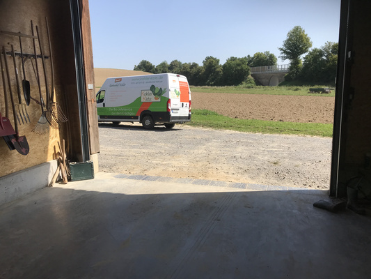 KI generiert: Blick aus einer Scheune auf einen Lieferwagen mit "Kohler Kiste" und Felder im Hintergrund.