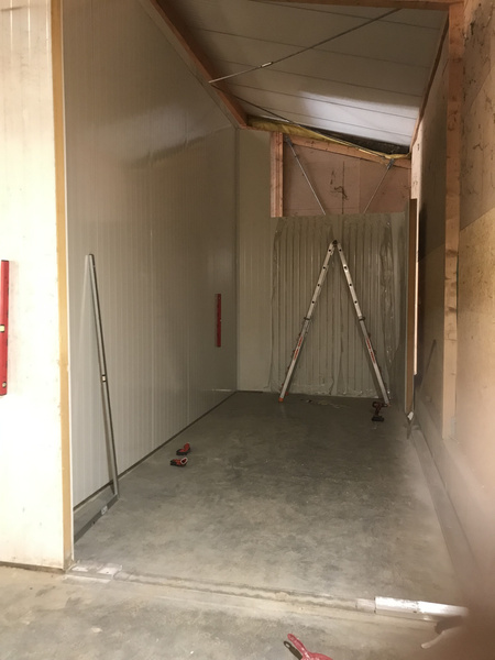 KI generiert: Eine leere, teilausgebaute Halle mit Leiter und Werkzeugen auf dem Boden.