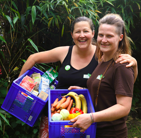 KI generiert: Zwei Personen halten Kisten mit frischem Obst, Gemüse und Produkten.