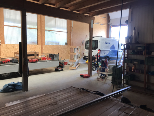 KI generiert: Werkstatt mit Fahrzeugen, Werkzeugen und Regalen; ein Lieferwagen hat die Aufschrift "Koch".