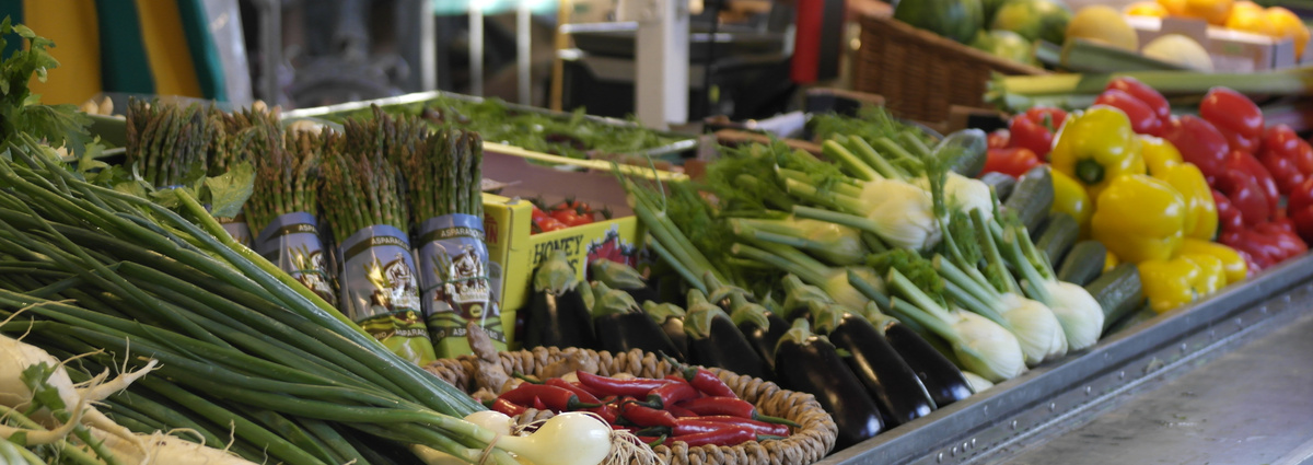 KI generiert: Ein Marktstand mit frischem Gemüse: Spargel, Paprika, Fenchel und Frühlingszwiebeln.