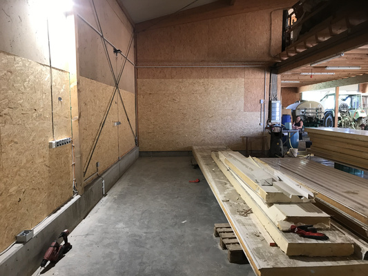 KI generiert: Innenansicht einer Werkstatt mit Holzstapeln und Werkzeugen auf einer Palette.