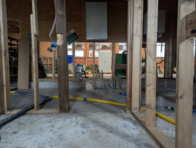 KI generiert: Das Bild zeigt den Rohbau eines Gebäudes, der mit Holzrahmen, freiliegenden Kabeln und Geräten ausgestattet ist. Im Hintergrund sind verschiedene Bauwerkzeuge und Materialien zu sehen.